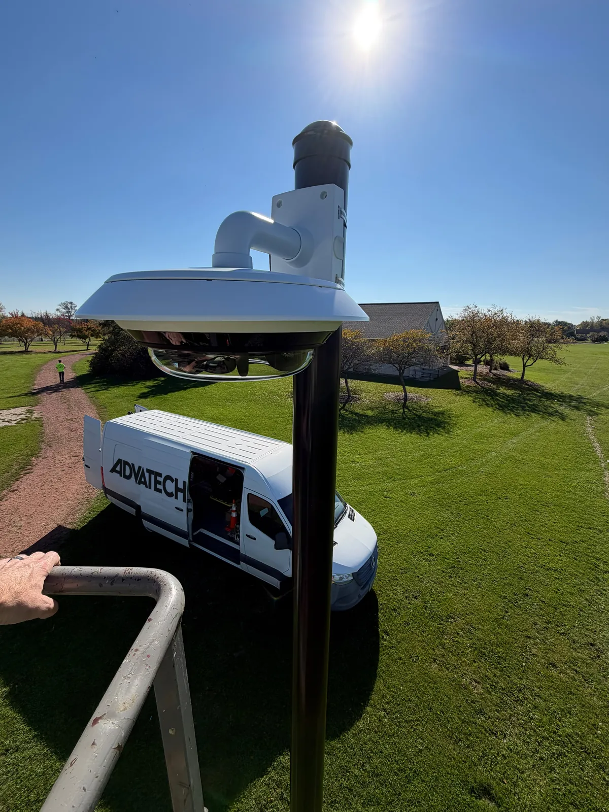 Axis multi-sensor camera on a pole at a City of Mequon park, with the AdvaTech Security van parked on the grass below