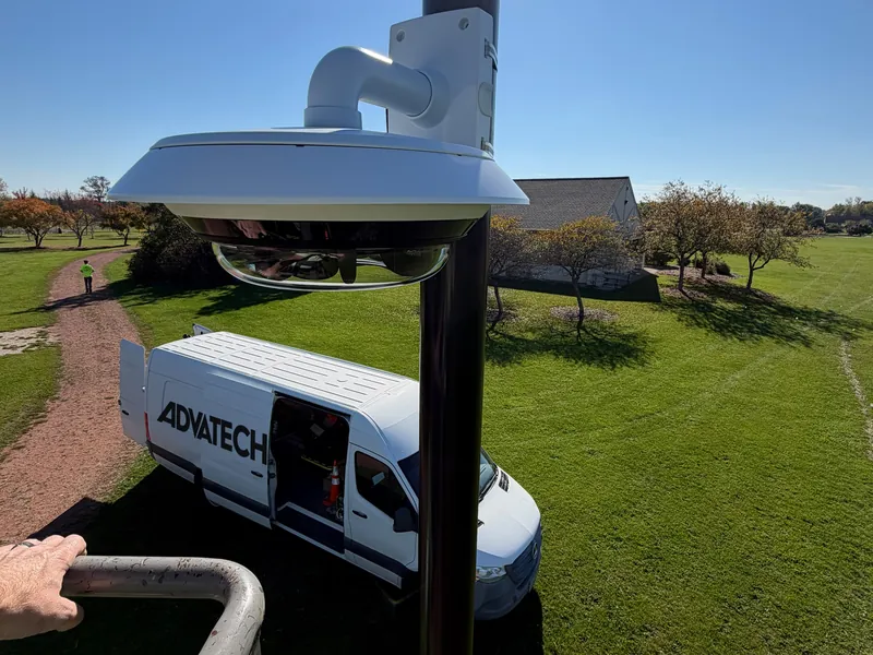 Axis multi-sensor camera on a pole at a City of Mequon park, with the AdvaTech Security van below