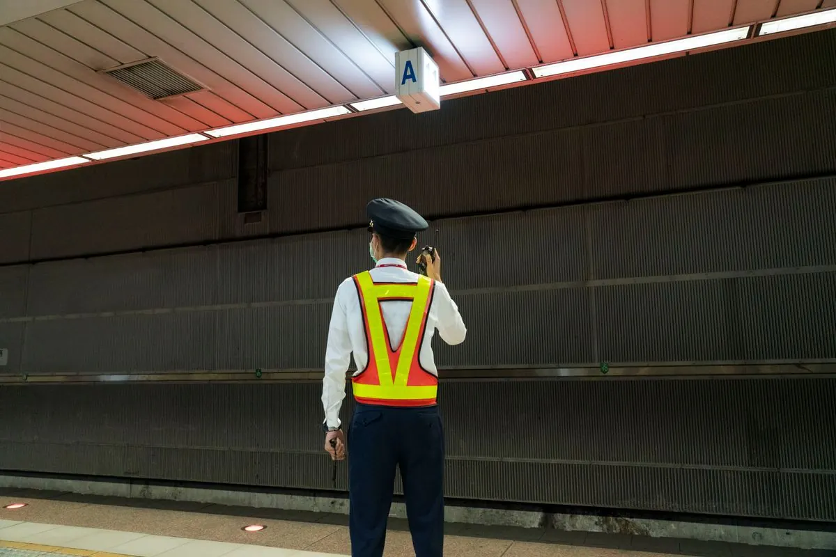 A security guard seen from behind, holding a radio