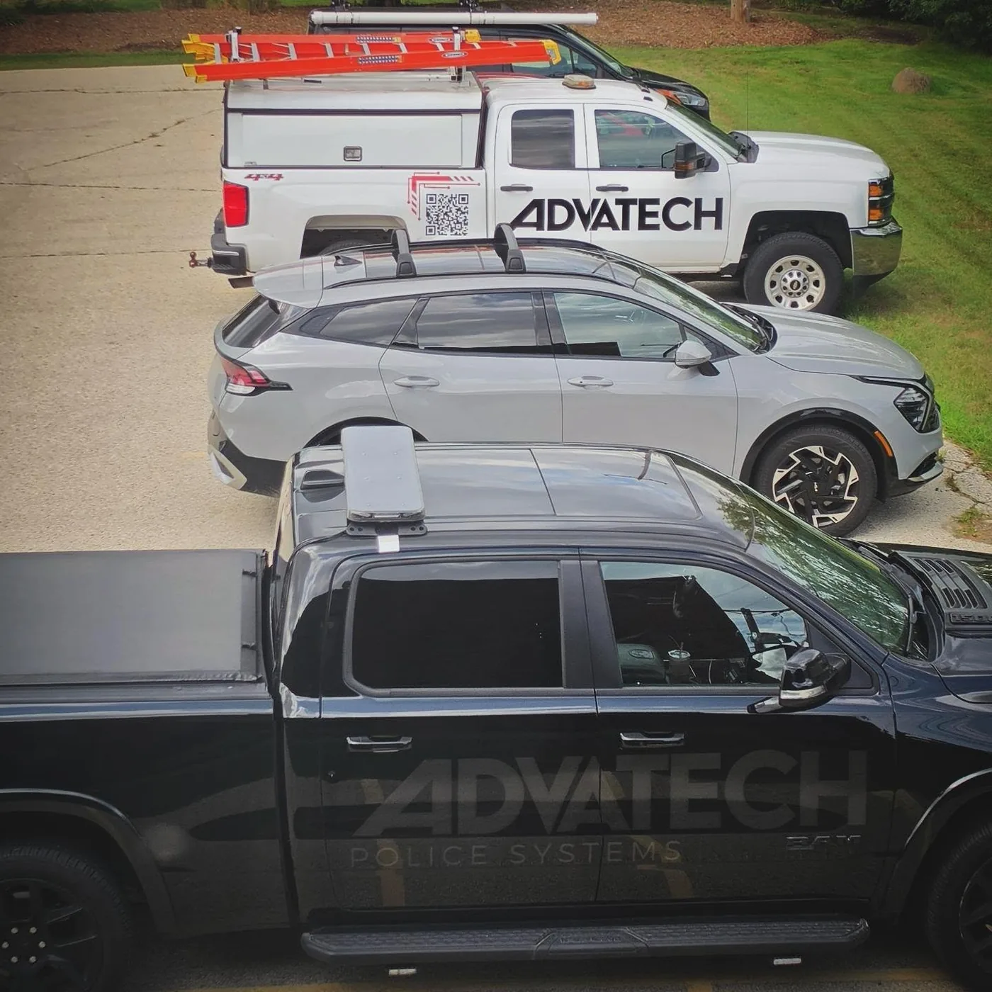 A white AdvaTech service truck and a black pickup, with the company name on the truck door
