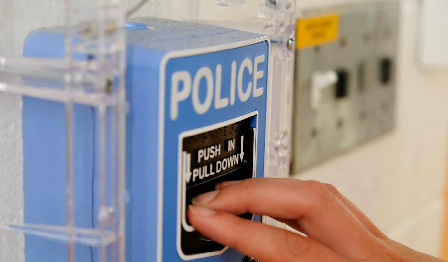 A hand pulling the lever on a blue POLICE panic station.